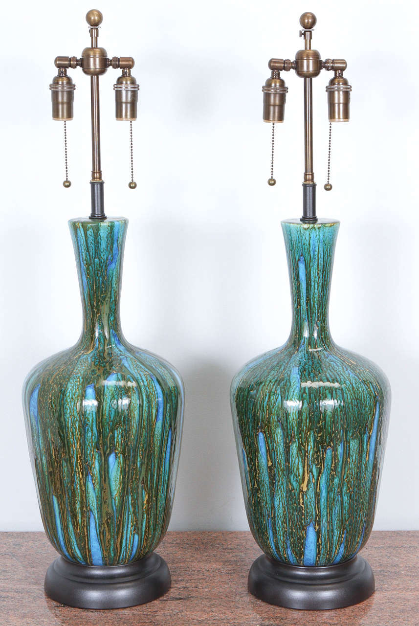 Lovely pair of ceramic table lamps with a gorgeous blue and green drip glaze. The glaze has a glassy translucence that gives it depth. Here and there you will find crackling which reveals flecks and streaks of gold.
They are newly rewired with