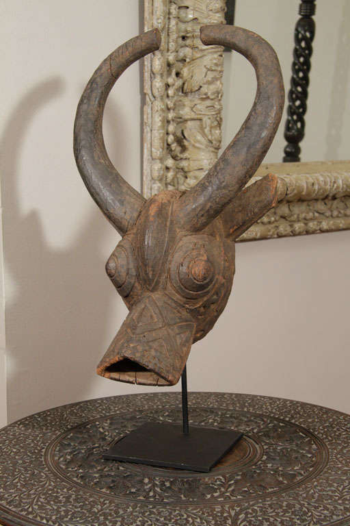 The horned mask decorated overall with incised geometric designs. The mask early 20th century. Mounted on stand.