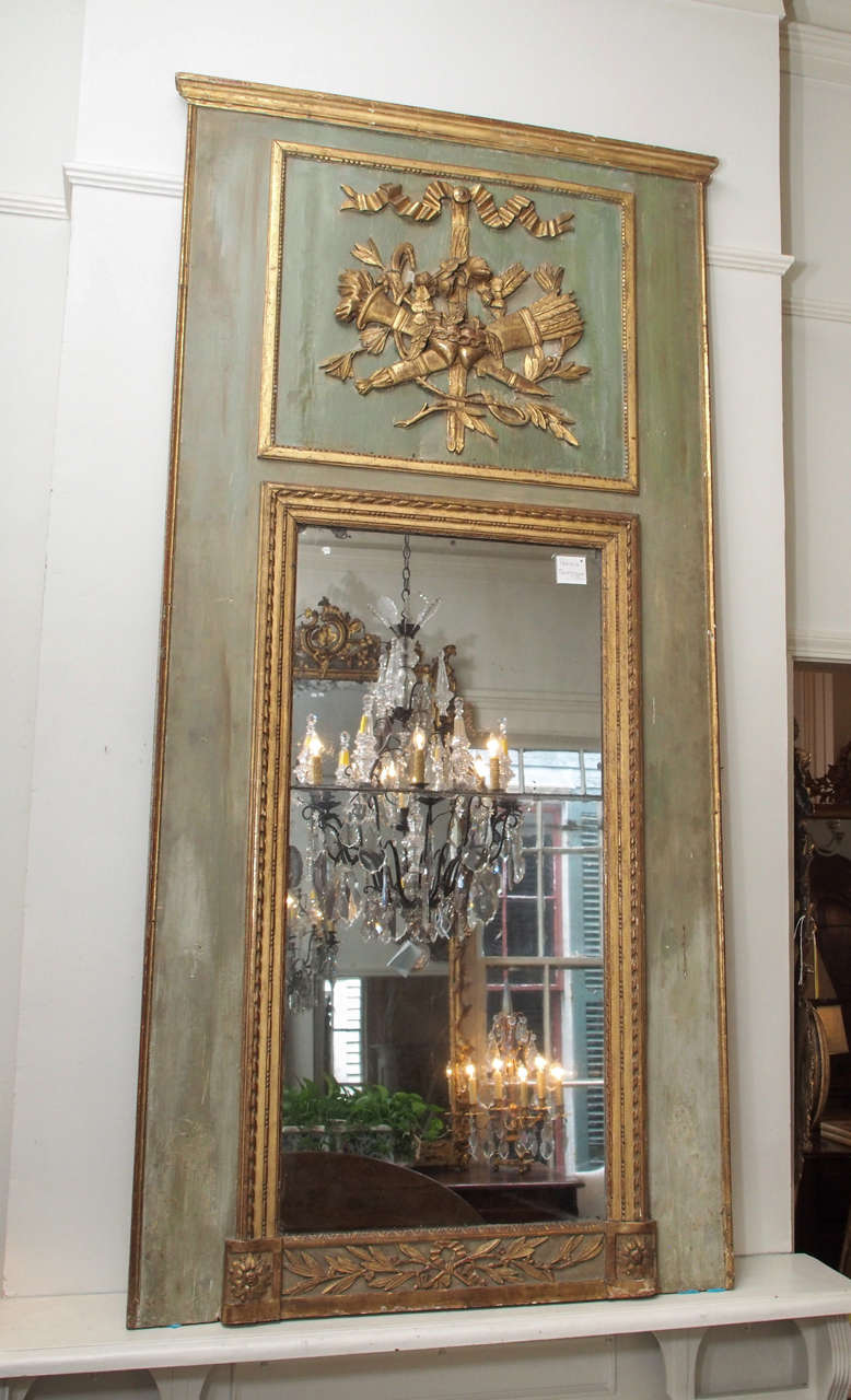 Early 19th century Louis XVI style trumeau  mirror with carved gilded wood in a torch and arrow motif and painted in green. Split glass