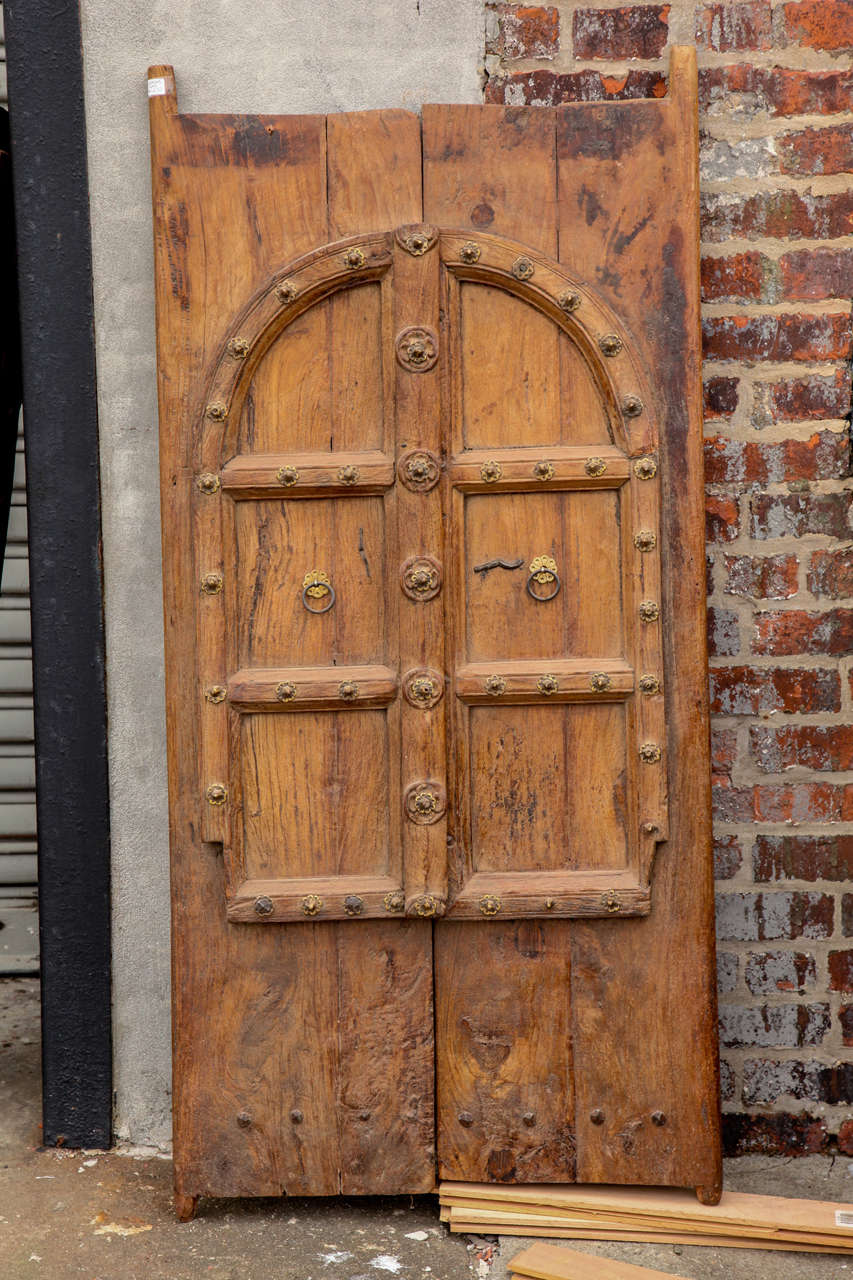 A pair of rustic antique doors with arch motif hand carved from solid teak wood, with metal stud accents. 19 th century. from Rajisthan . priced for the pair, free shipping within the continental U.S.A.