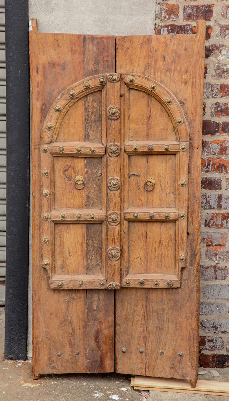 A rustic pair of doors with arch motif, hand carved in solid teak with metal escutcheons . Great original patina, and lovely joinery work accented with studs.