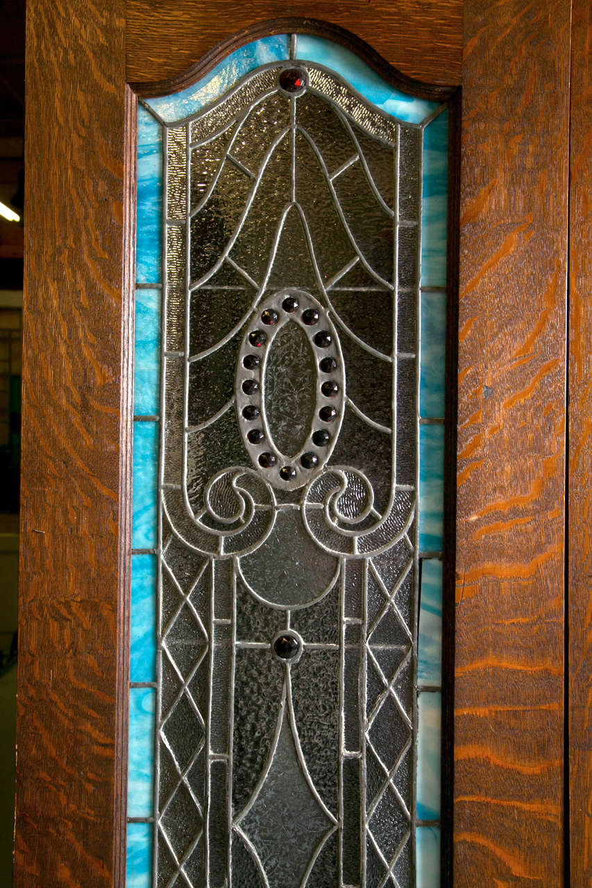 This is an exquisite pair of antique handmade bejeweled stain glass doors. Nice Art Deco style detailing with gorgeous vibrant bright blue perimeter color. The glass has a textured finish.  The panels are bejeweled with 15 jewels in a ruby red
