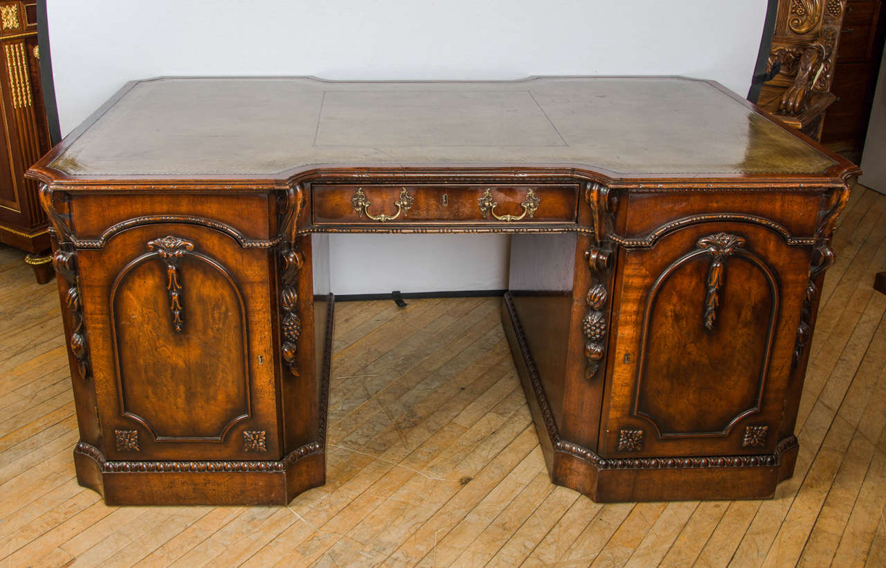 A very handsome and excellent quality mid-20th century. Chippendale style mahogany partners pedestal desk that features a breakfront design and mottled green leather tooled top. The desk has attractive bits of carving with fruit swags along the side