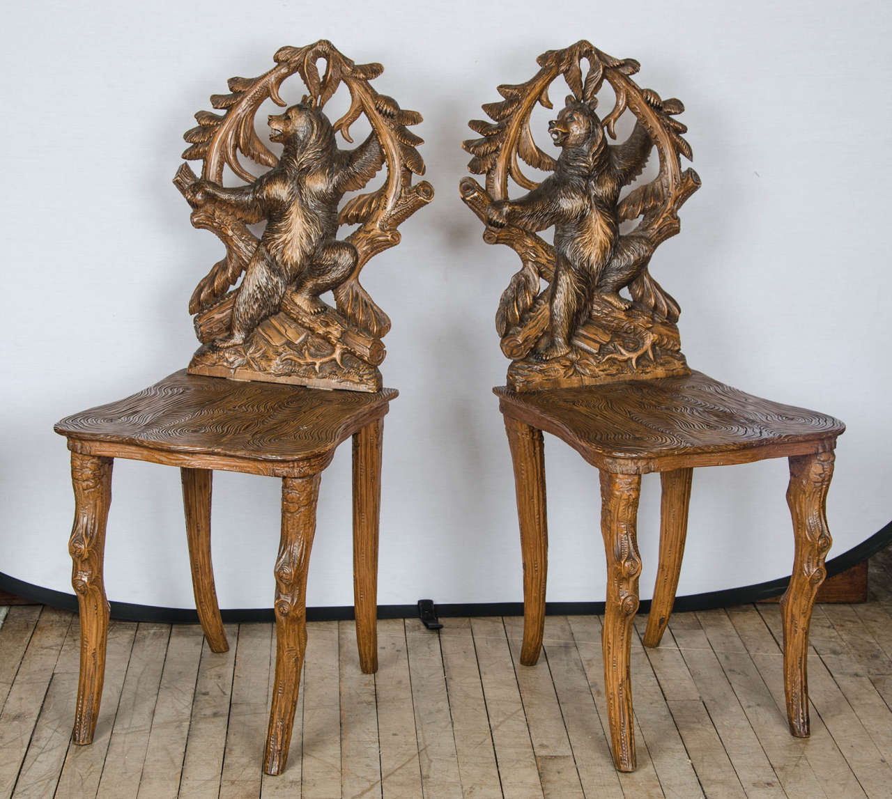 This magnificent 19th C. set of 8 black forest side chairs depicting a bear climbing have been superbly hand carved. The chairs stand on roughly carved legs with knotted ‘knee’ joints. Each chair measures approximately 17 in – 43 cm wide, 17 ½ in –