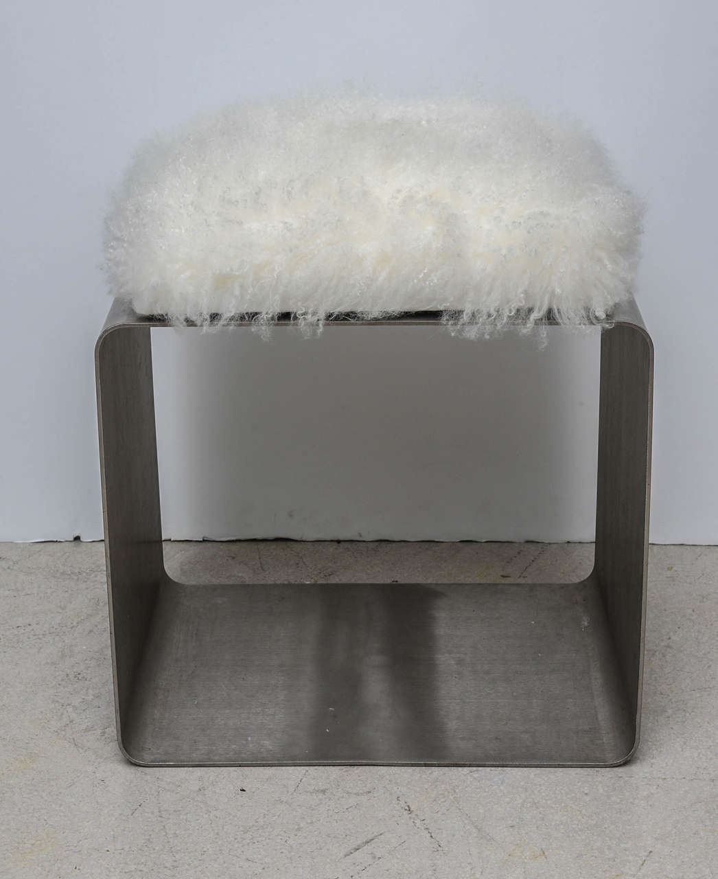 Simple stainless steel cube bench with a Mongolian lamb fur seat.