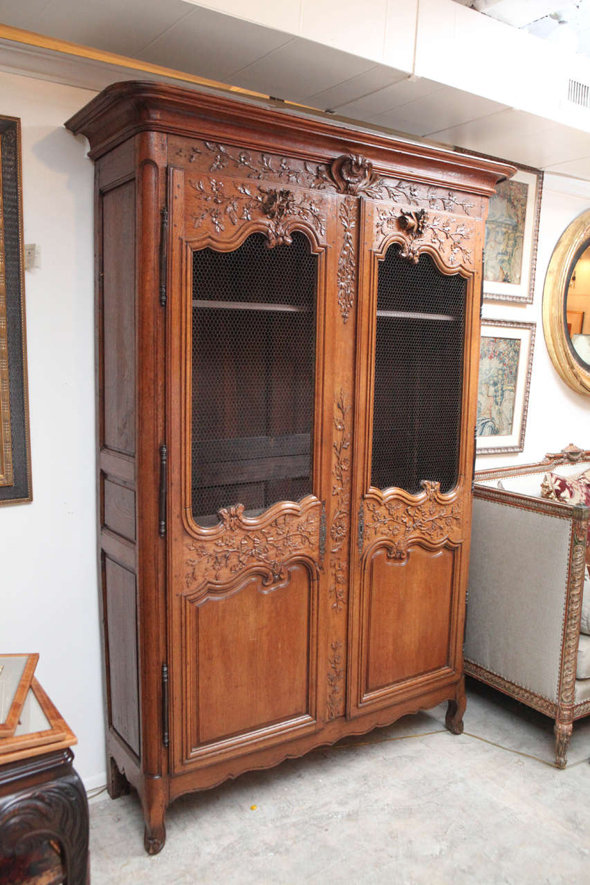 Late 18th century French oak vitrine with floral vine ribbon motif. The vitrine has chicken wire doors and there are four shelves which are not original. The original key is included.