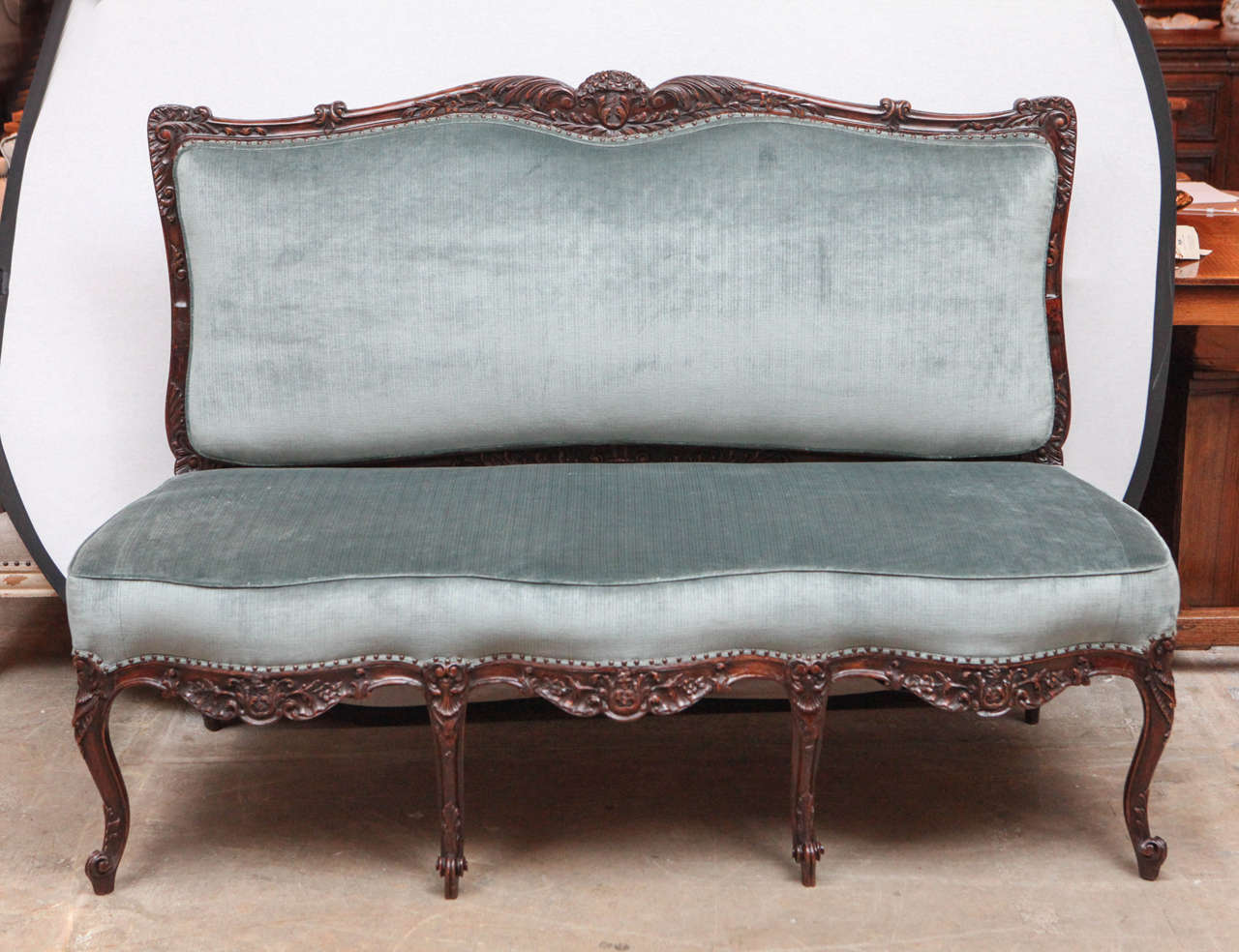 19th century French beautifully carved walnut armless settee with flower basket motif. The settee has been newly upholstered in velvet with nailhead detailing.