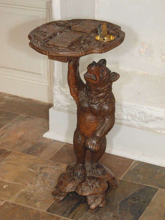 Great example of Black Forest furniture. This bear is standing holding a tray with compartments for matches and tobacco and an ashtray. His head is hinged and lifts to reveal another compartment. Wonderful intricate carving and details.