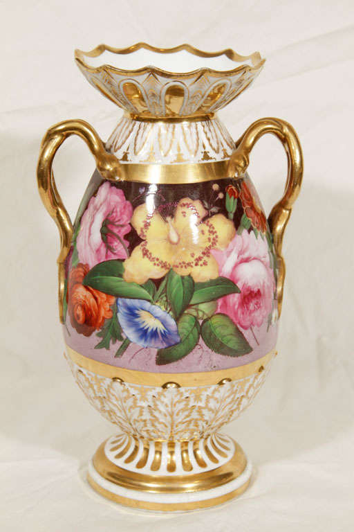 A pair of Coalport vases show the lavishly painted flowers of an English garden. Above and below the flowers are white and gilt leaves. At the side of each vase is a pair of gilded snake form handles.
 The Coalport factory began production in 1795