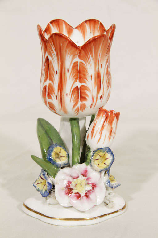 A pair of orange and white porcelain tulips each with a smaller tulip bud, pansies and green leaves on a white base with gilt trim. In this period porcelain flowers were made by several of the English factories.