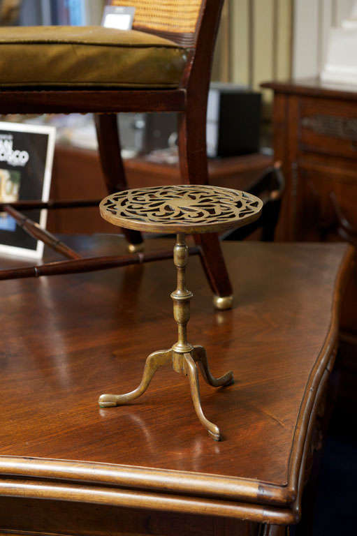 The round top with pierced circular scroll patterns raised on turned standard supported on tripod base ending in padded feet.