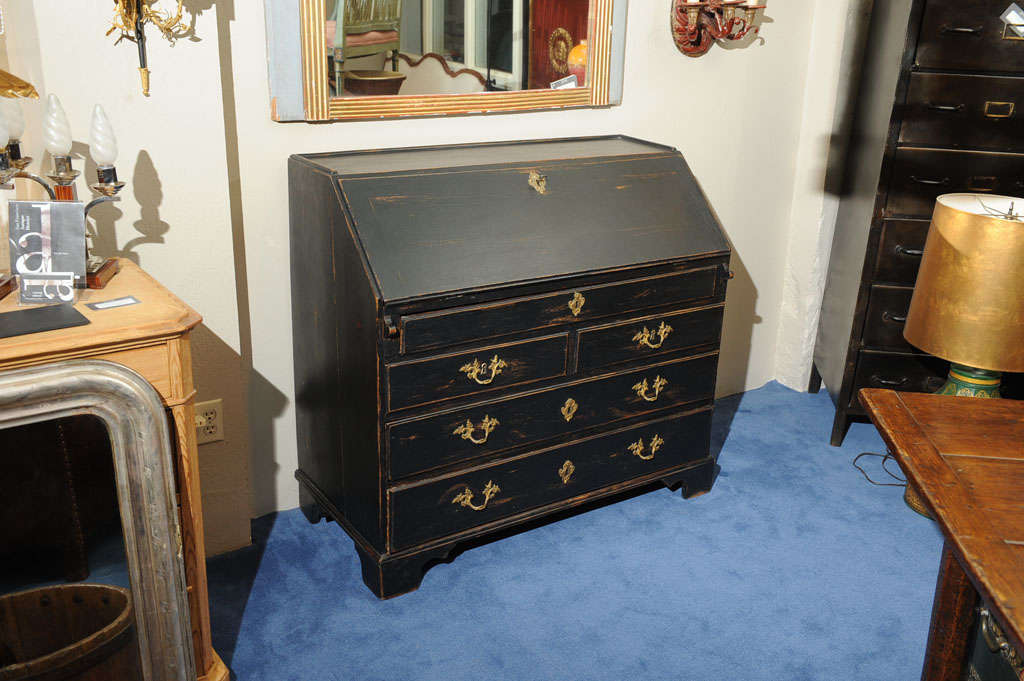 The rectangular top with slanted fall front opening to reveal a red-painted interior of fitted drawers and folio holes flanking a central convex cupboard over a rectangular case fitted with a long drawer, two short drawers and two graduated long