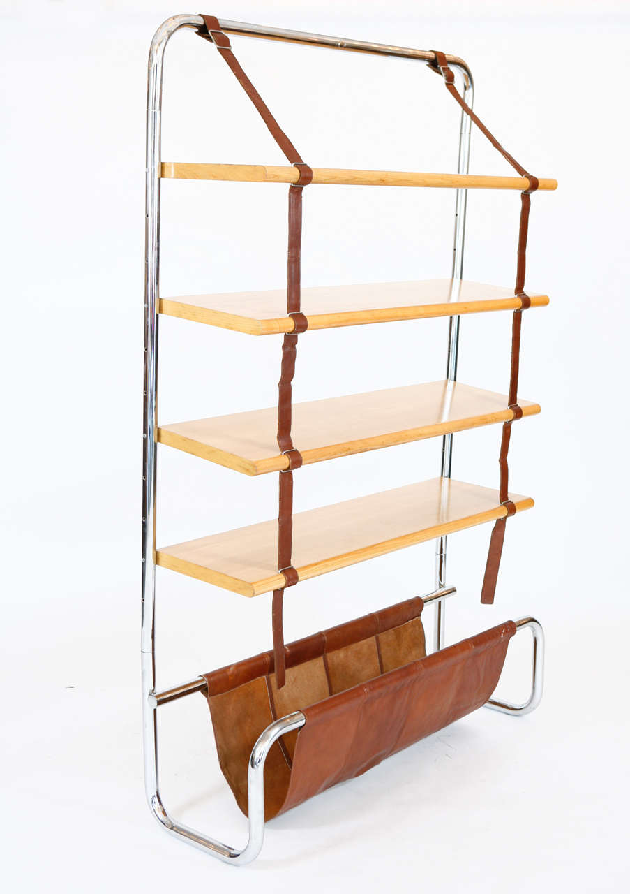 Impressive large scale Italian wall shelf designed by Luigi Massoni for Poltrona Frau, 1971. Chromed tubular steel frame with natural wood shelves suspended by brown leather straps. Gorgeous brown saddle leather catch all at base - perfect for