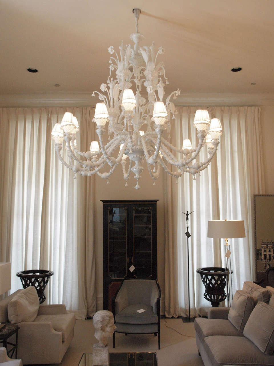 Spectacular and grand 16-light chandelier in milk-glass of highly unusual form with four large c-chaped stems replacing the more typical central stem;  heavily decorated throughout with blown glass leaves, daffodils, and bell-flowers, the arms