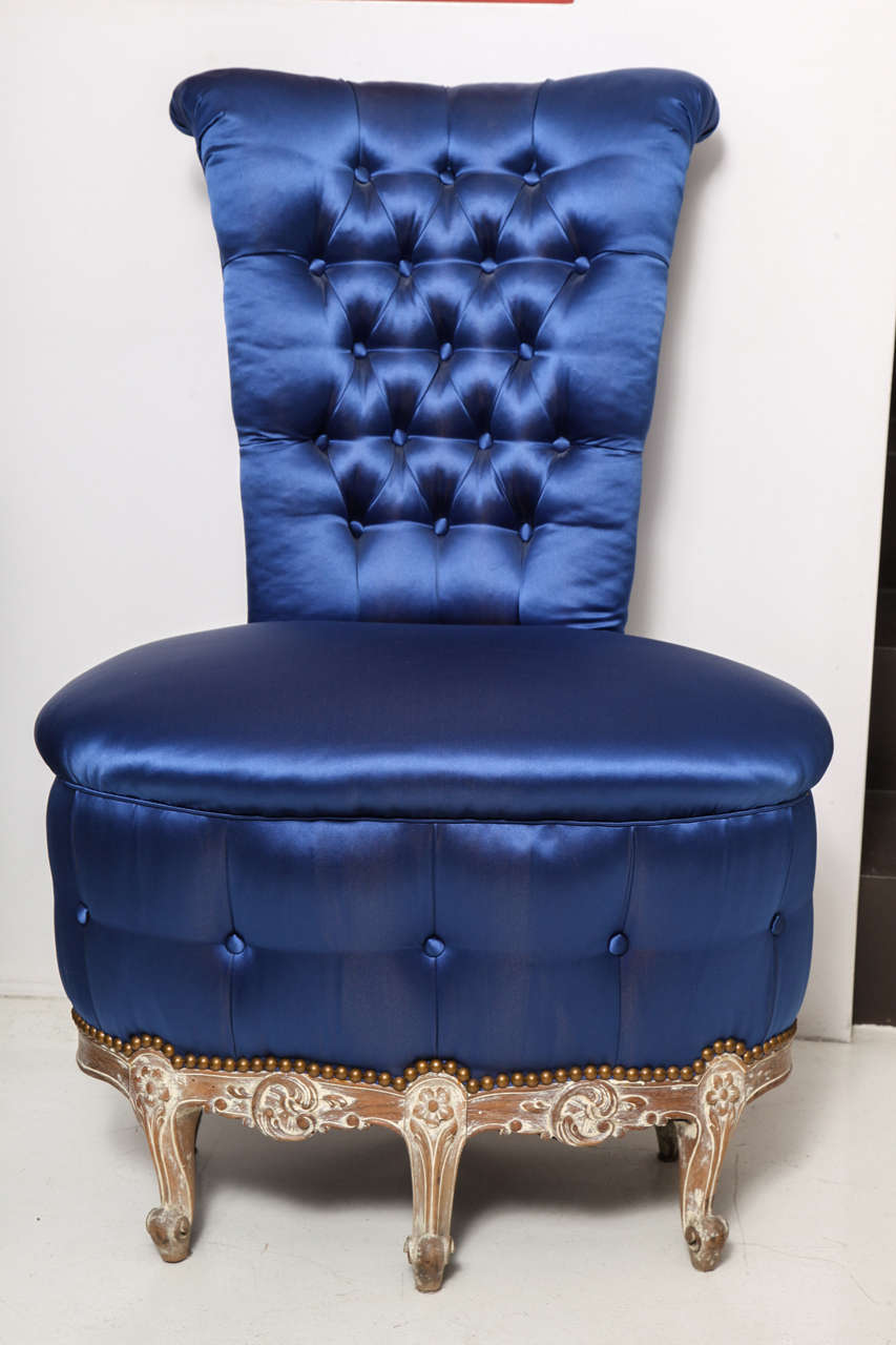 Occasional chair with oval seat and narrow scrolling back with tufted blue upholstery and carved floral decoration on the base.