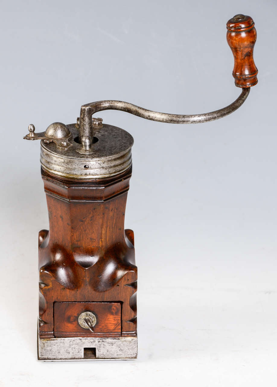 A sculptured walnut coffee grinder. Signed 