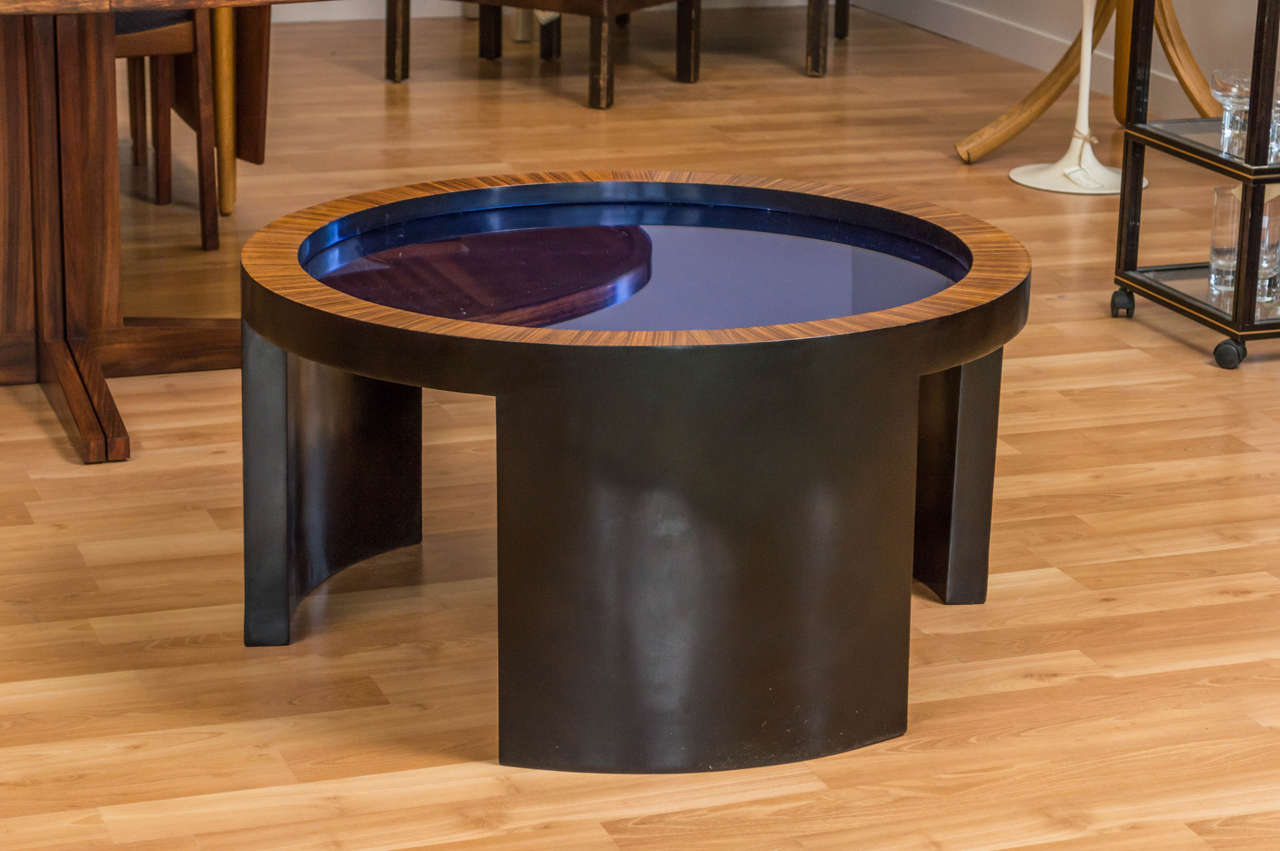 A wonderful round coffee table, attributed to Gilbert Rohde. Very dark chocolate  brown base with what we believe to be Macassar Ebony veneer around the outer edge, in the middle you'll find a cobalt blue mirror