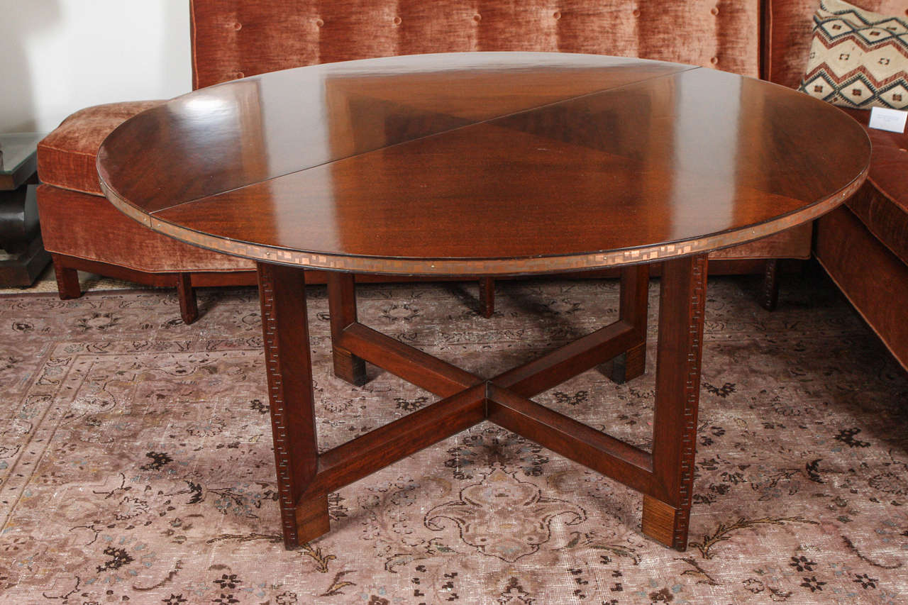 Rare Frank Lloyd Wright for Heritage Henredon, Taliesin table. The low dining table features a solid mahogany base with the Taliesin motif carved into each leg. The top of the table has incredible wood graining and is trimmed in solid polished