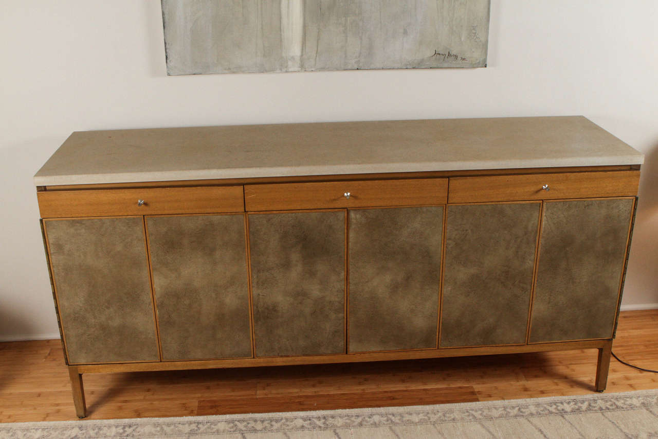 Paul McCobb for Calvin credenza with granite top over three drawers and two tri-fold doors enclosing interior storage.
