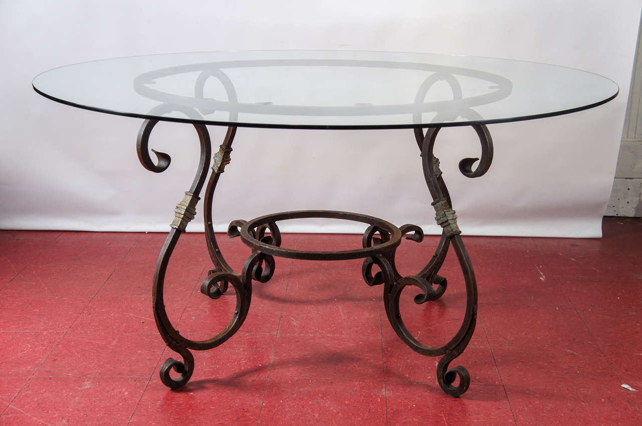 This rustic and elegant French Baroque style iron round table with glass top can be used indoor or outdoors. Thick scrolled hand forged iron base with a rust finish. A perfect breakfast room table that will sit six or eight. Top and base can be sold