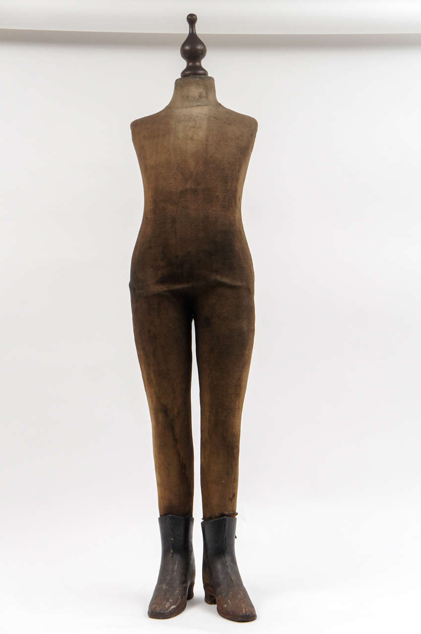 Rare and exceptional mannequin in a child size, wearing worn cloth and metal shoes. The piece is in stable condition, with some holes and evidence of wear in the cloth. The right hip is slightly disjointed, and can be easily moved into place. An