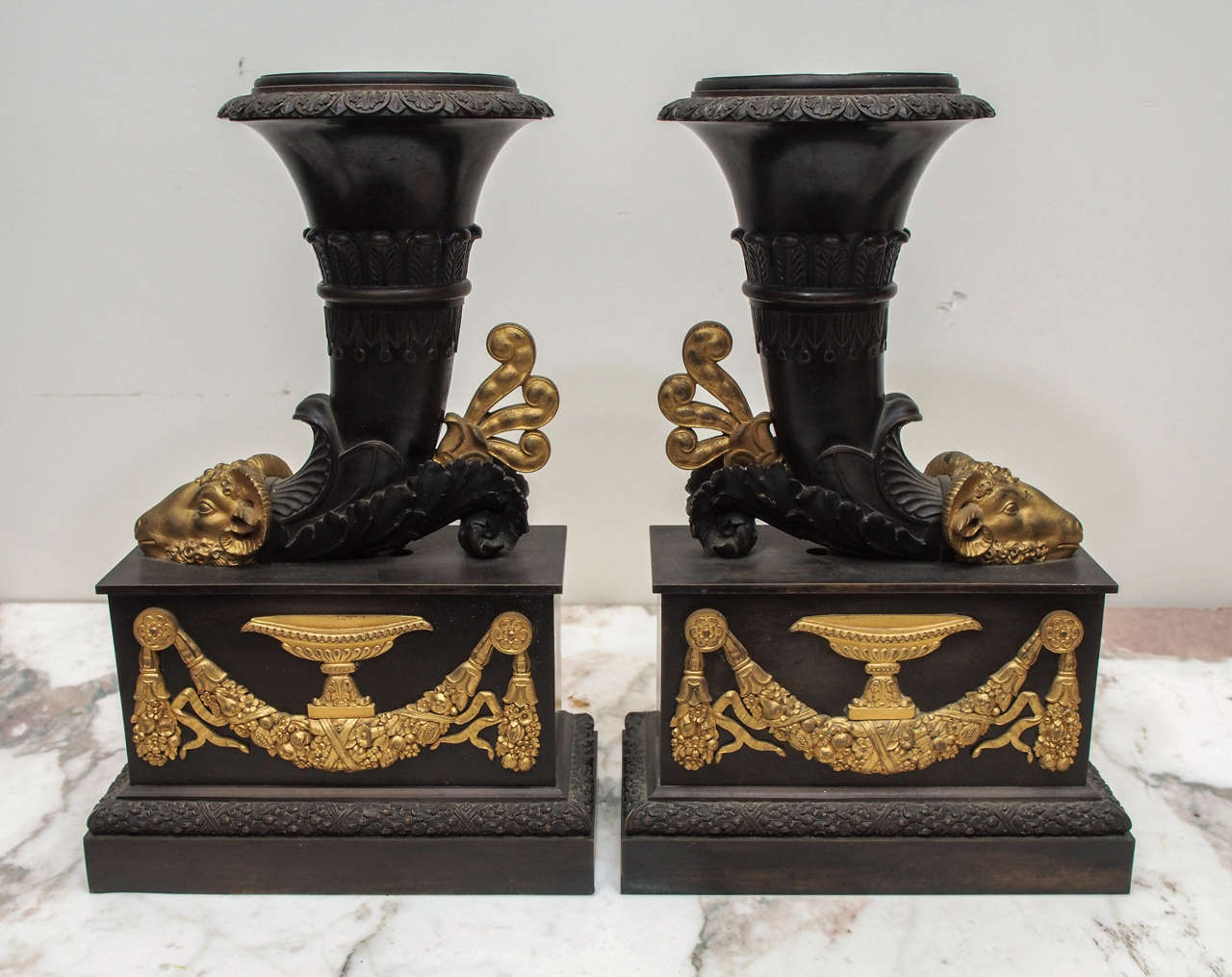 Pair of French 19th c. Classical Cornucopia Form Vases with Rams Heads and Folate Swags and urn decoration in Gilt Bronze on Patinated Bronze.
