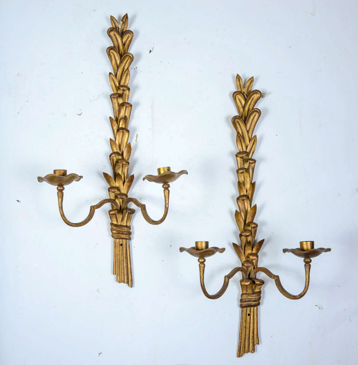 Pair of 1940s - 1950s sconces in gilt leave wrought iron representing a bundle of leaves held by a stylized ribbon. Two lighted arms with gilt wrought iron sconces and cups.

Can be wired on demand.