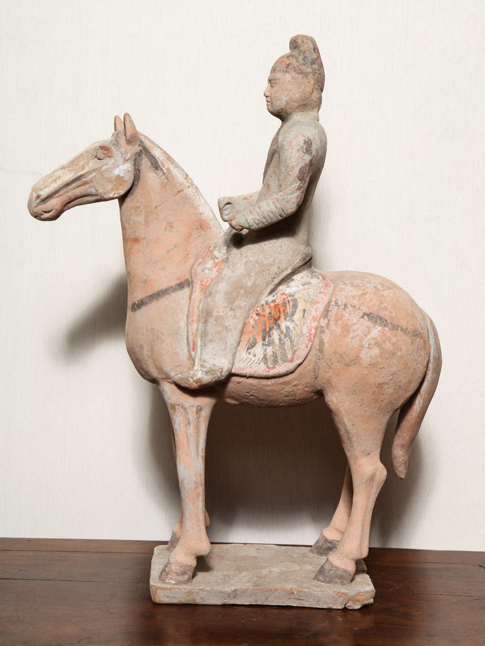 A Chinese Tang dynasty terracotta horse with rider sculpture from the 7th-10th century. This statuette of a horse with rider was made in terracotta during the Tang dynasty (618-907 A.D.), which is regarded as the Classic age of China. Despite its