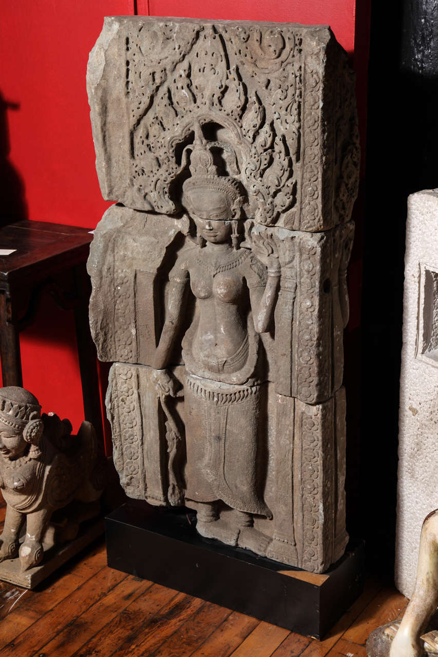 A Khmer stone temple carving of female spirit Apsara from the 12th or 13th century on custom base. This Apsara 'Dancer' sculpture comes from a Cambodian Khmer temple, where it was carved in stone during the 12th or 13th century. This almost