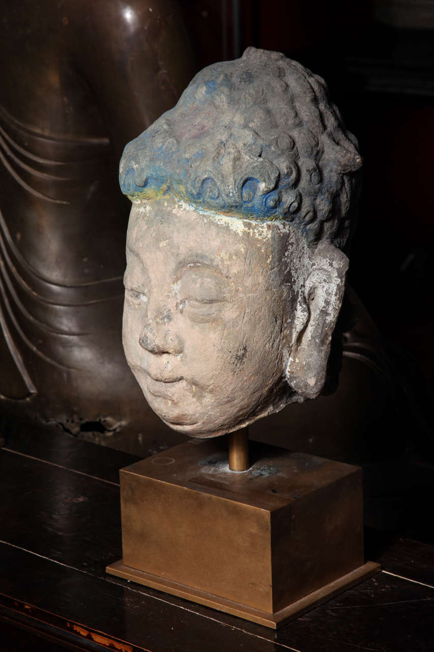Larger than life-size hand carved stone Buddha head with some remains of vintage pigments. Ming Dynasty ( 1368 A.D. - 1644 A.D. ), China. Mounted on a bronze plinth.
