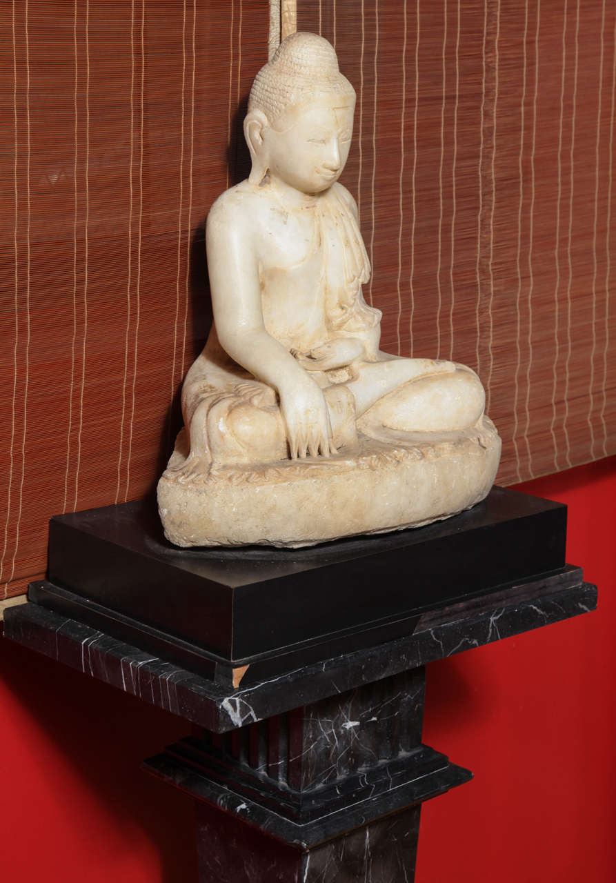 A Burmese Mandalay style early 19th century carved alabaster sculpture of a sitting Buddha. This Buddha sculpture seated in the attitude of “calling the earth to witness” was hand-carved from alabaster in Myanmar, circa 1800, in a typical Mandalay