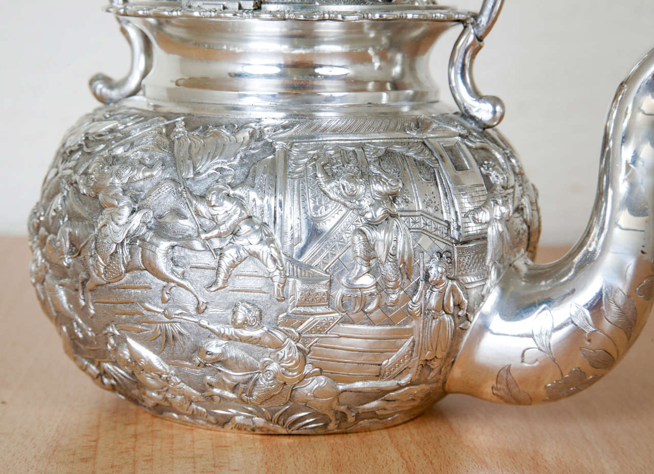 A Chinese Export Silver Kettle of round form embossed with figural court and battle scenes and with dragon handle and finial. It is marked KMS, for Kwong Man Shing, Hong Kong circa 1880. It is 23cms to the top of the fixed handle, and weighs 800gms.