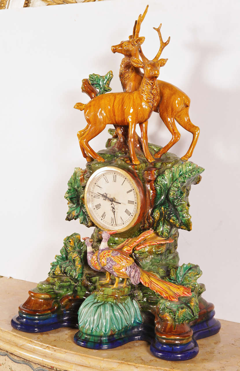 Large early 20th century barbotine mantel clock from France, circa 1920, featuring two stags standing on top of a working condition clock (battery operated) and two colorful birds watching on. Standing nearly 40