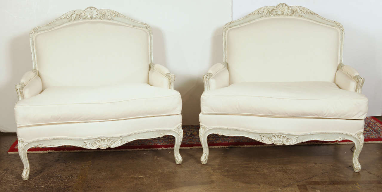 Pair of oversized antique painted bergere armchairs from France, circa 1880. The carvings show great detail and the frame and seating are covered in white toile. A great addition to any living area or bedroom. Excellent condition with rich painted