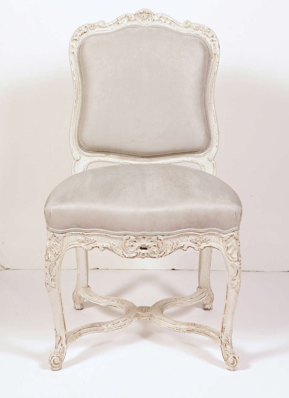 Nicely carved set of eight painted side chairs from the Provence region of France, circa 1880, all reupholstered with grey ultra suede fabric. These chairs have a wide and deep seat to fit any dining or breakfast room table. Intricate carvings with