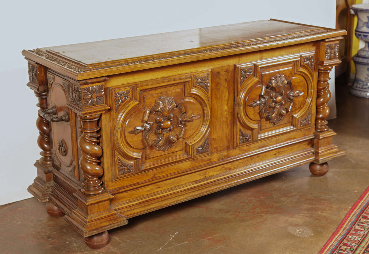 19th century carved walnut trunk/blanket chest with rich patina featuring relief carvings on both front panels and heavy iron handles on either side. This piece sits on bun feet and opens completely to provide great storage.