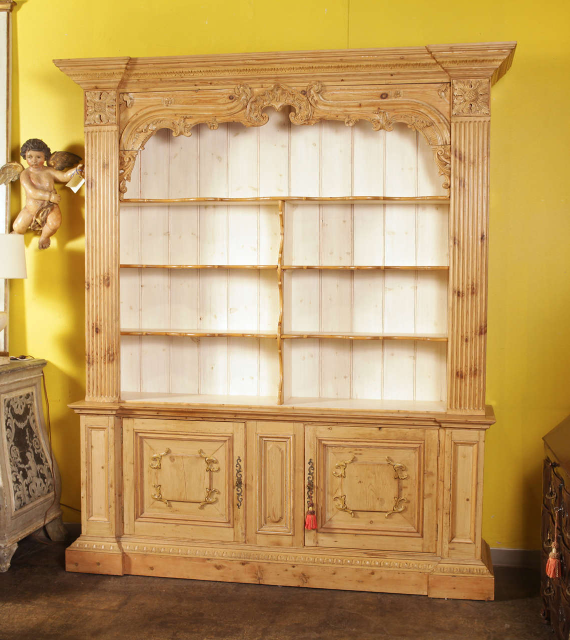 Elegantly carved Louis XIV pine bookcase finished with a light white wash. The   upper display section features 3 permanent shelves and off white paint complements the inside back. A wonderful compliment to any library, study or den setting.