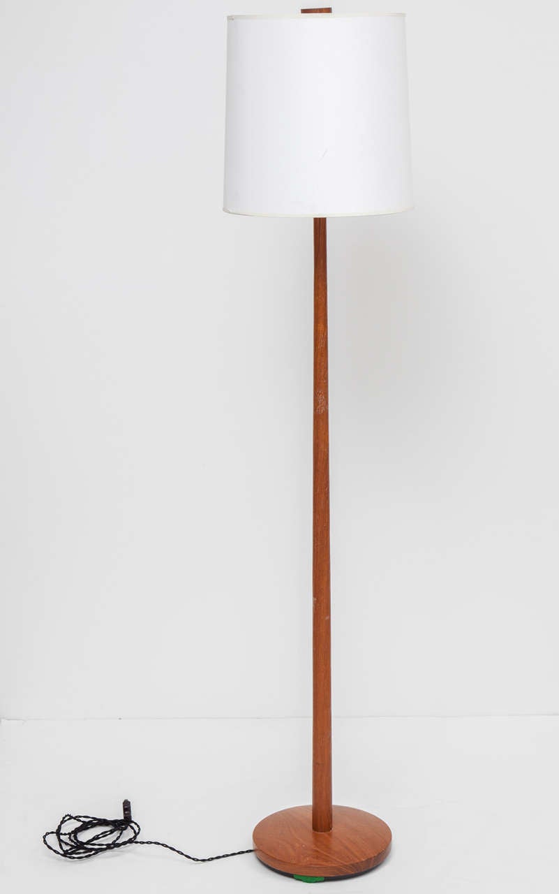 Teak floor lamp with tapered dowel stem and round base.  Sweden, circa 1960. Includes off-white tall drum shade and matching wood finial.  Rewired for U.S. with French black silk twist cord; takes one standard bulb, 75 watts