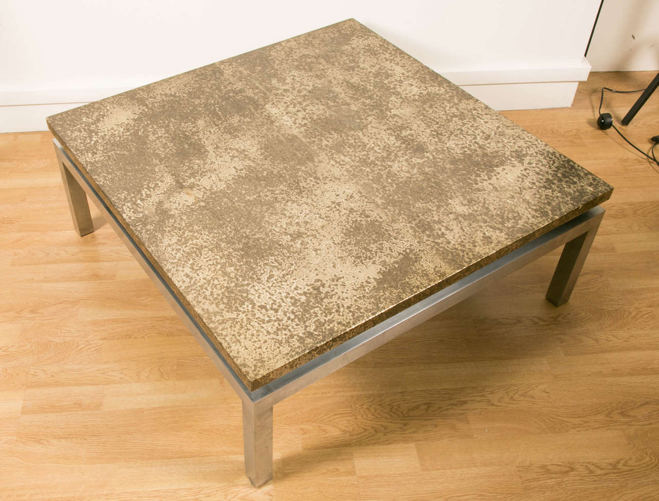 Large square coffee table with stainless steel base square section. Top covered with a sheet of acid oxidized brass coated with a clear lacquer cracked like the ancient Chinese lacquer. 1970s work.