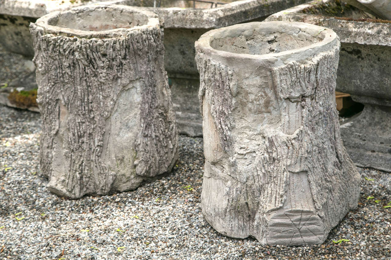 A pair of handcrafted faux bois planters in the form of tree trunks with realistic bark detail.