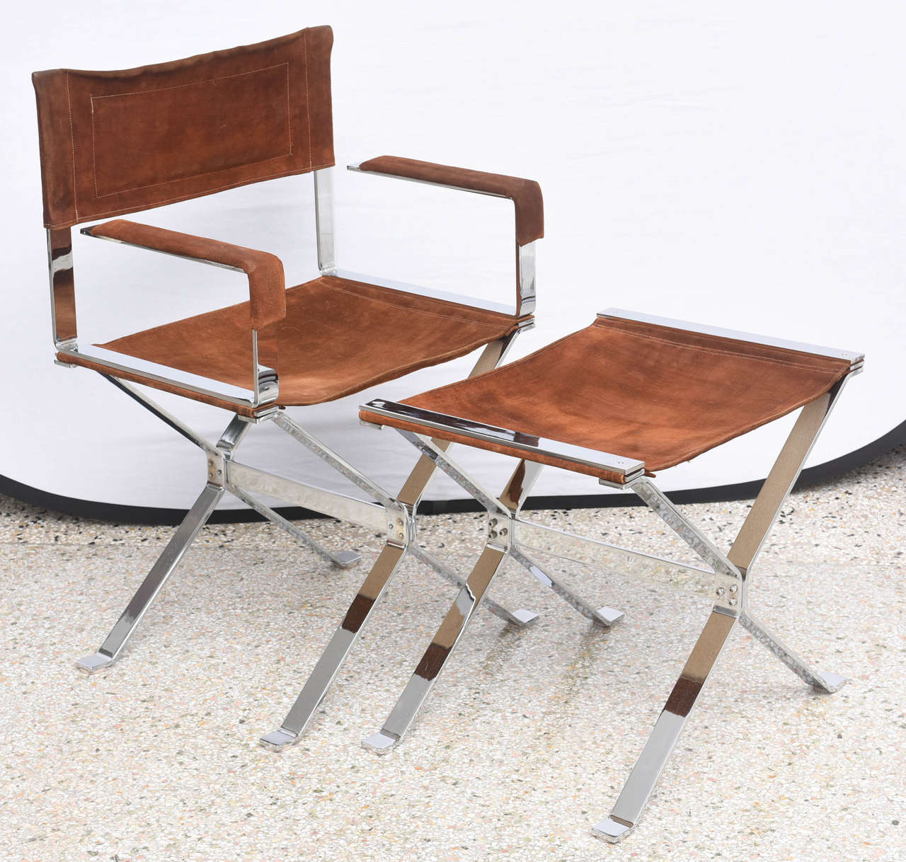 This pair of chairs were produced in the 1960s by the iconic furniture designer Alessandro Albrizzi  and are the height of Mid-Century European design.  The polished steel frames are softened by the use of cognac colored suede that has aged to a