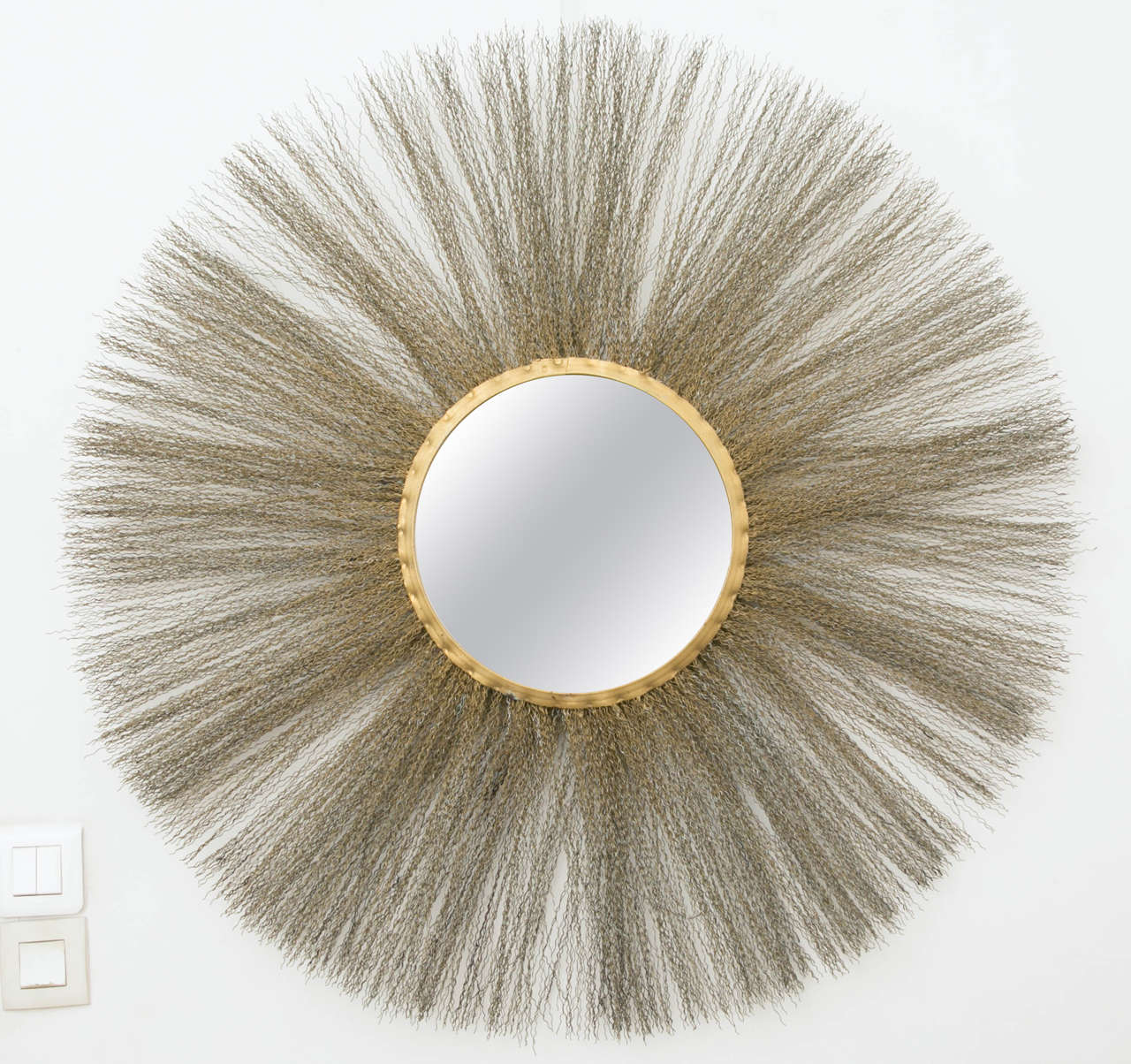 Astonishing circular gilt brass mirror, Italy, 1950.
Frame surrounded with many zig-zag brass threads.
Mirror own frame diam.12 inches . Hair length 1 ft. 