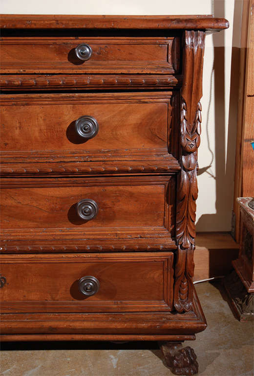 Handsome, four-drawer, hand-carved walnut commode featuring faux-pilasters of cascading fronds. The whole fitted with original, brass hardware and sitting atop paw feet.