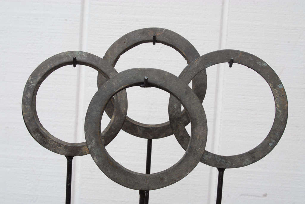 Set of four bronze sash buckles on museum stands. These metalwork circular ancient forms are coveted sculptures and decorative art pieces.