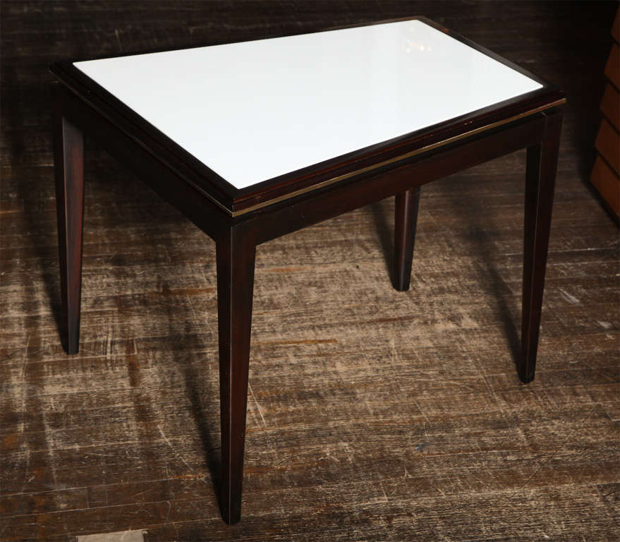 Wedge shaped table of dark stained wood, with brass trim and white Carrera glass insert top. Elegant form with nice detailing.