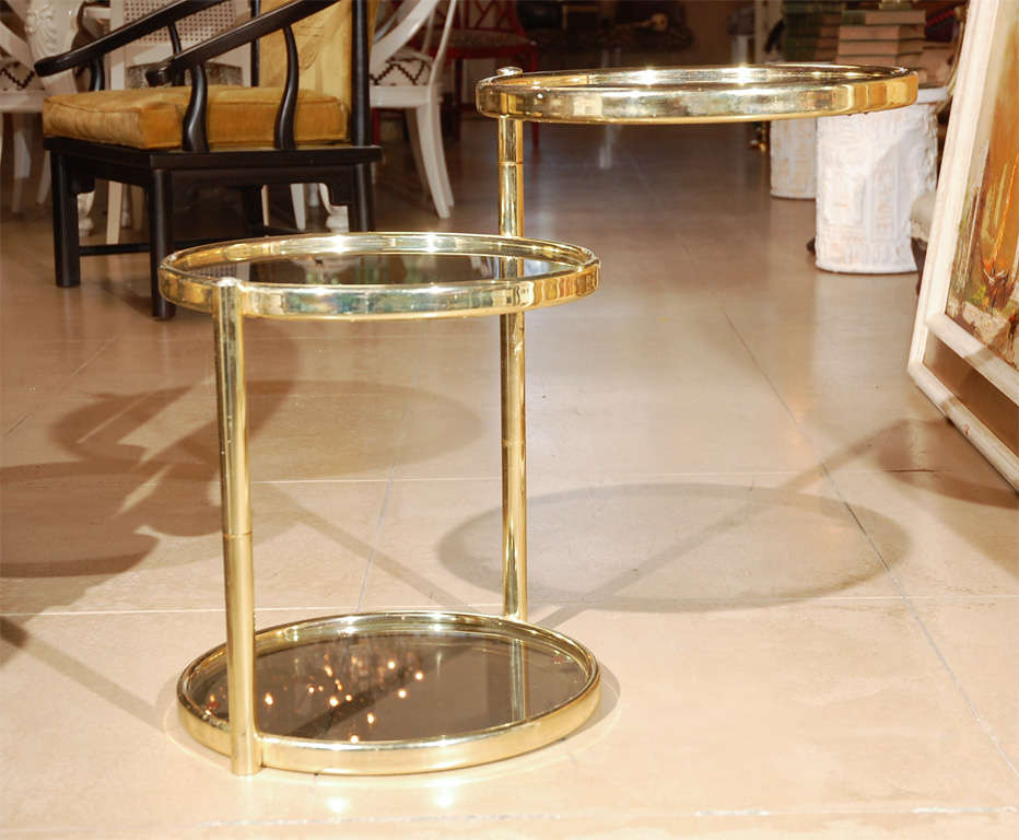 Polished brass frame swivel side table with smoked glass insets.