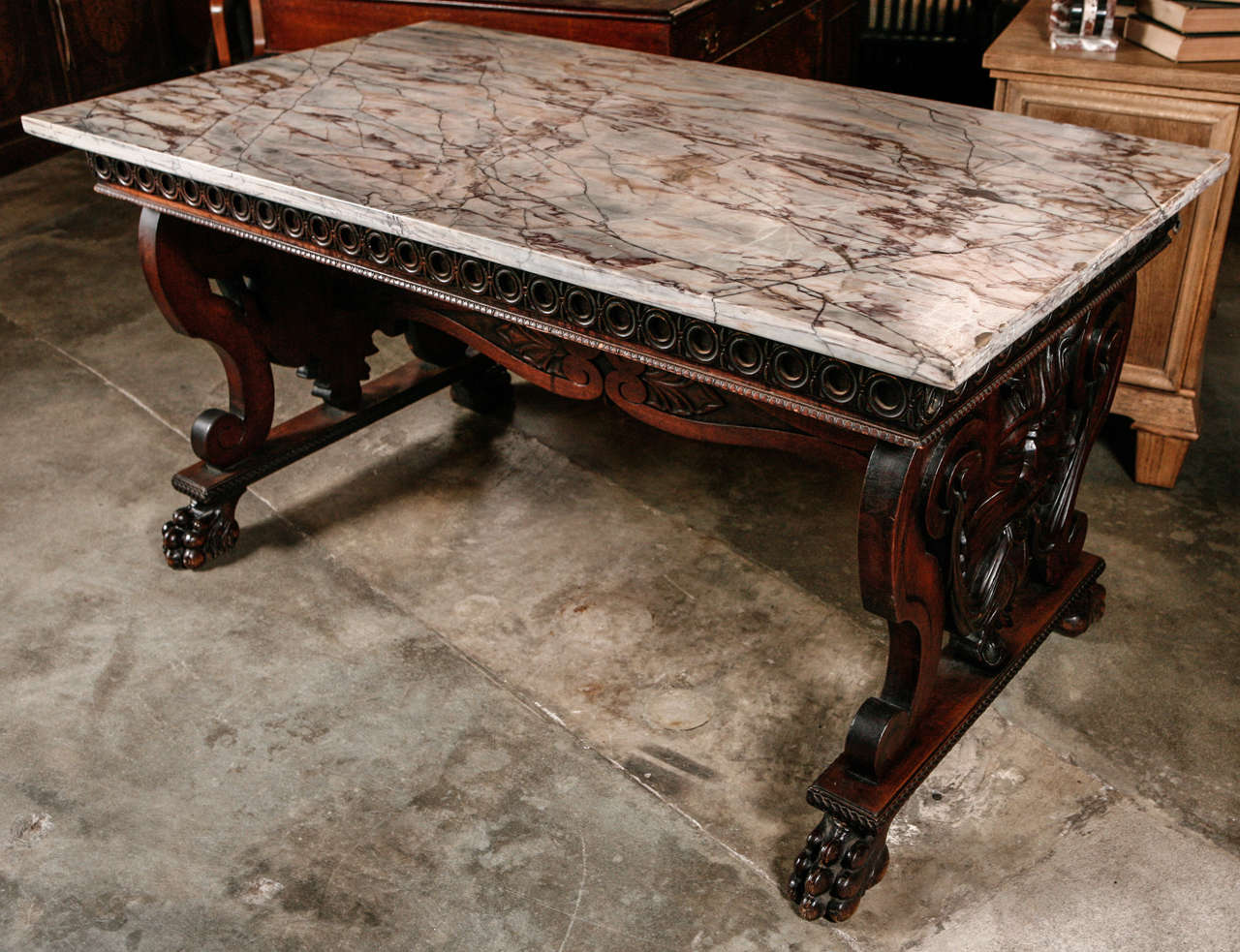 This substantial 19th century table has a variegated marble top which rests upon a base that is boldly carved with masks. This table will look good and fit into a number of settings, period or modern. It is considered American and 19th century. The 