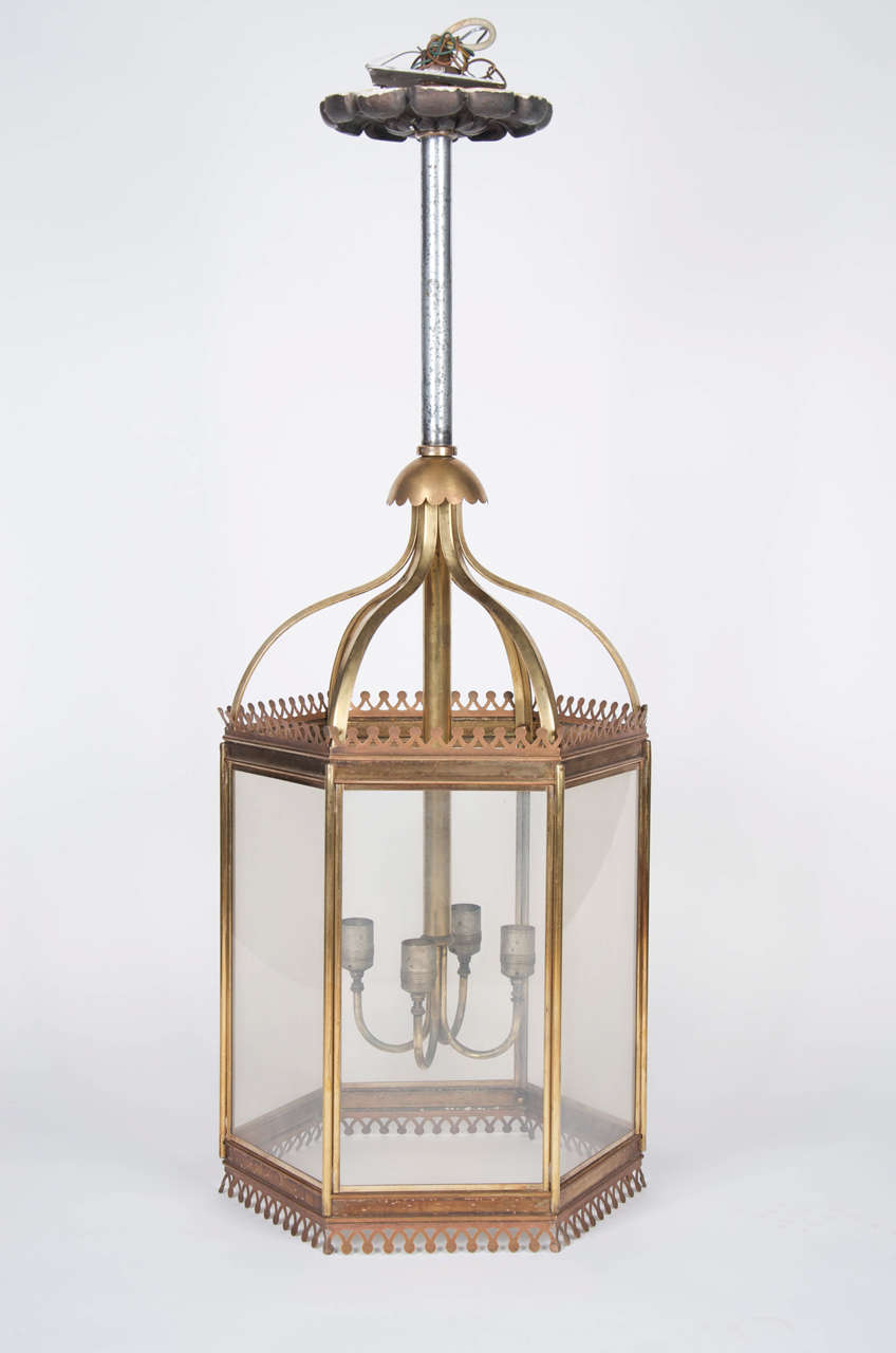 Impressive and imposing large brass lanterns with decorative copper fretwork edging the top and bottom. The lanterns have a domed brass top with a scalloped edge and hang on iron poles with decorative plaster ceiling roses at the top. The lanterns
