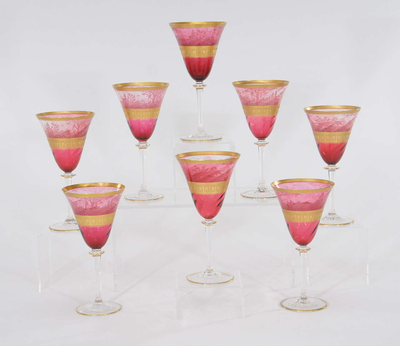 A collector's dream set. Eight extraordinary Moser water/ wine goblets in hand blown cranberry crystal. Not one, but a set of 8! The goblets are optic swirled and the top half is decorated with an acid-cut back cameo relief depicting a forest and