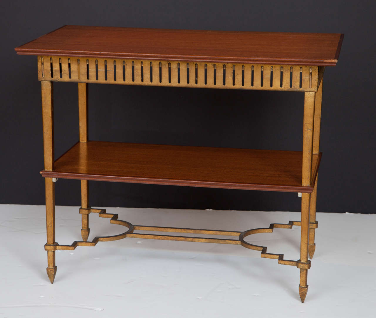 A unique and noteworthy table with a gilt iron frame with a mahogany top and lower shelf.  The pierced apron and stylized base make this table unique.  It can serve as a side table or can stand alone as a fabulous bar.